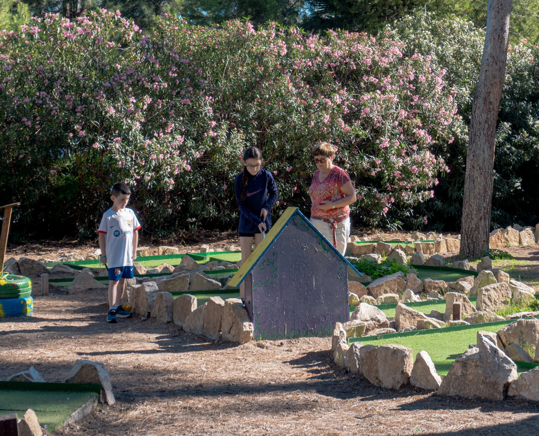 Niños y adultos jugando en el mini golf.