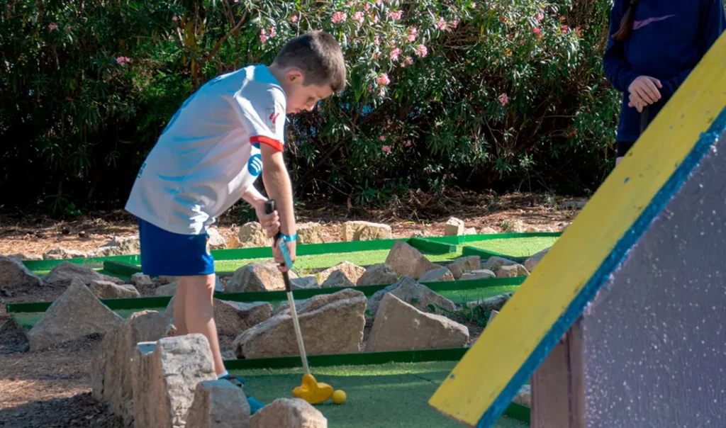 Niño jugando al minigolf al aire libre en Bosc Aventura Salou durante una fiesta de cumpleaños